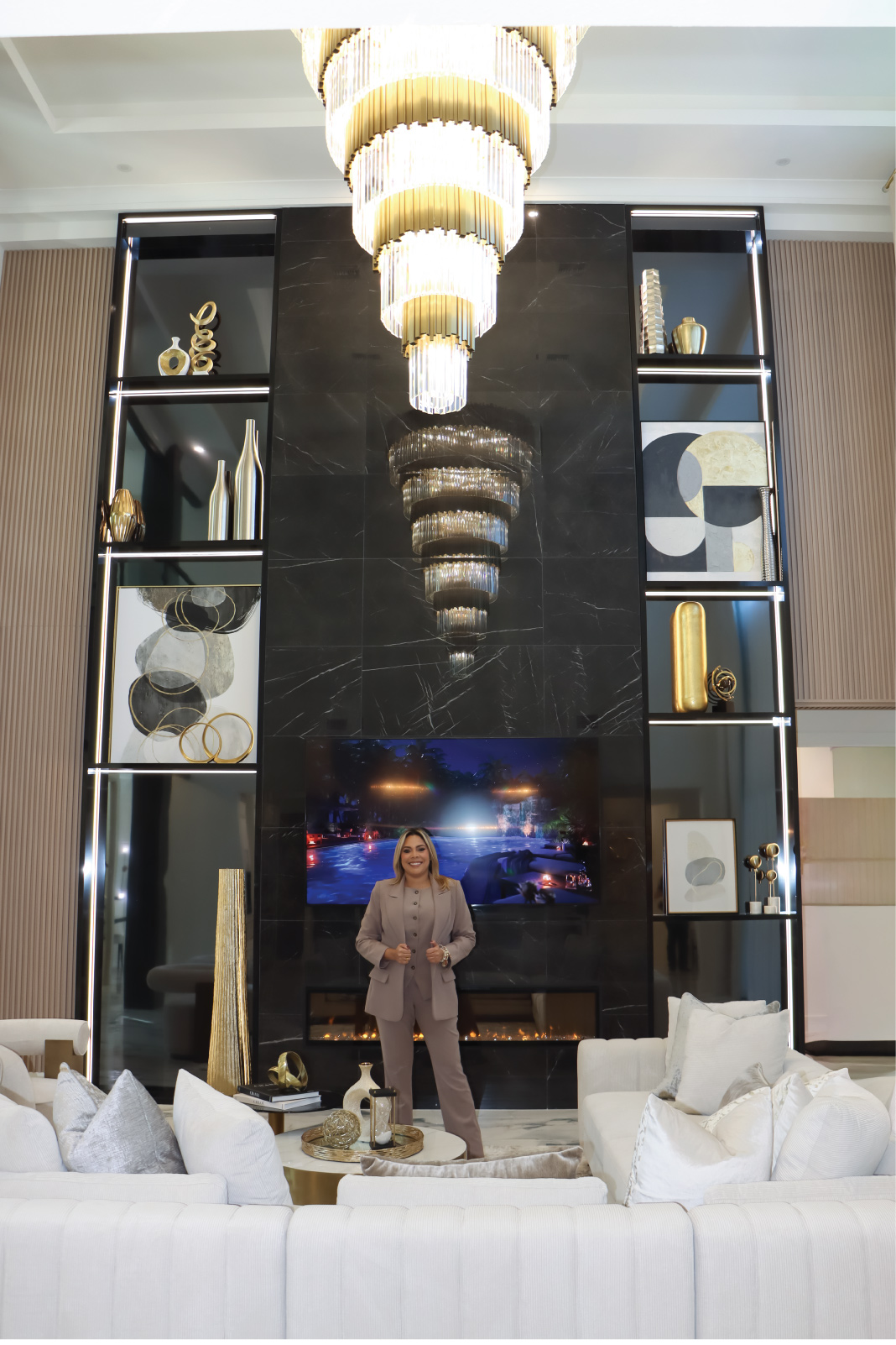 Luxury living room interior design in Lady Lake, Florida, showcasing a dramatic statement chandelier, black marble walls, white seating, and warm gold accents in a high-end home.