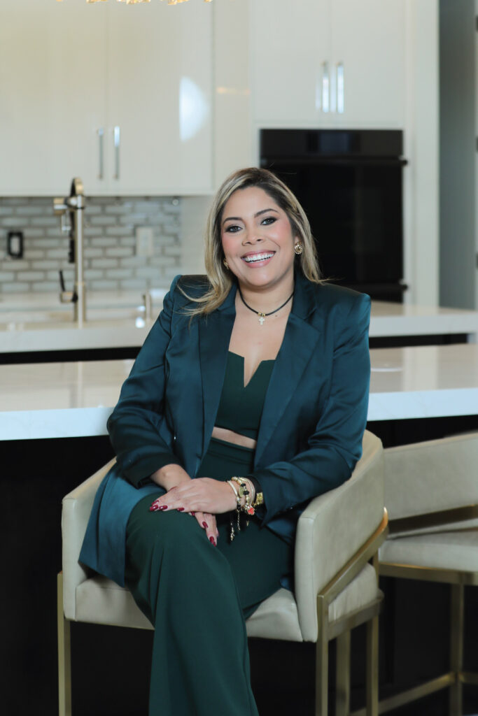 Zamira Ariza, luxury interior designer based in Orlando, Florida, seated in a modern kitchen setting, reflecting her refined approach to high-end residential interior design