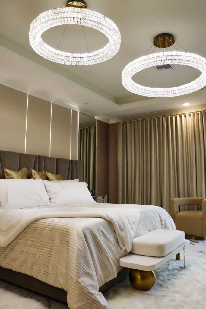 Contemporary luxury primary bedroom completed at Flaava House with designer lighting, upholstered headboard, warm rug flooring, and custom finishes.