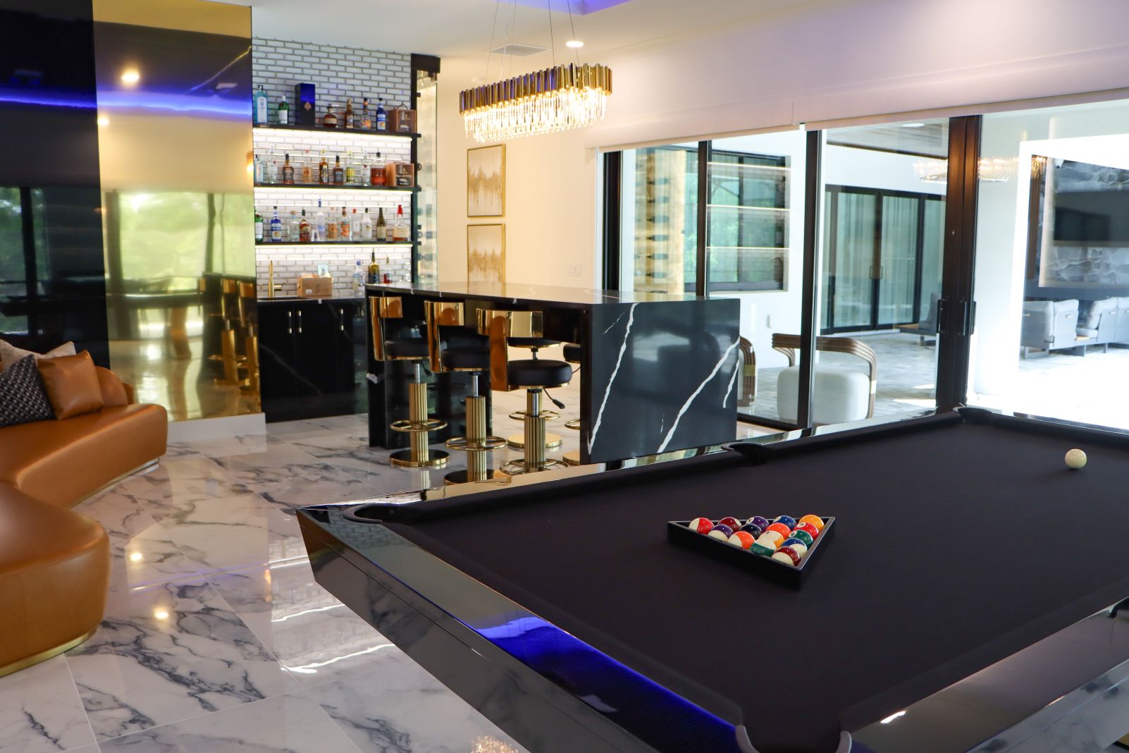 Luxury game room with custom billiards table, designer bar, and indoor-outdoor entertaining area at Flaava House in Lady Lake, Florida.