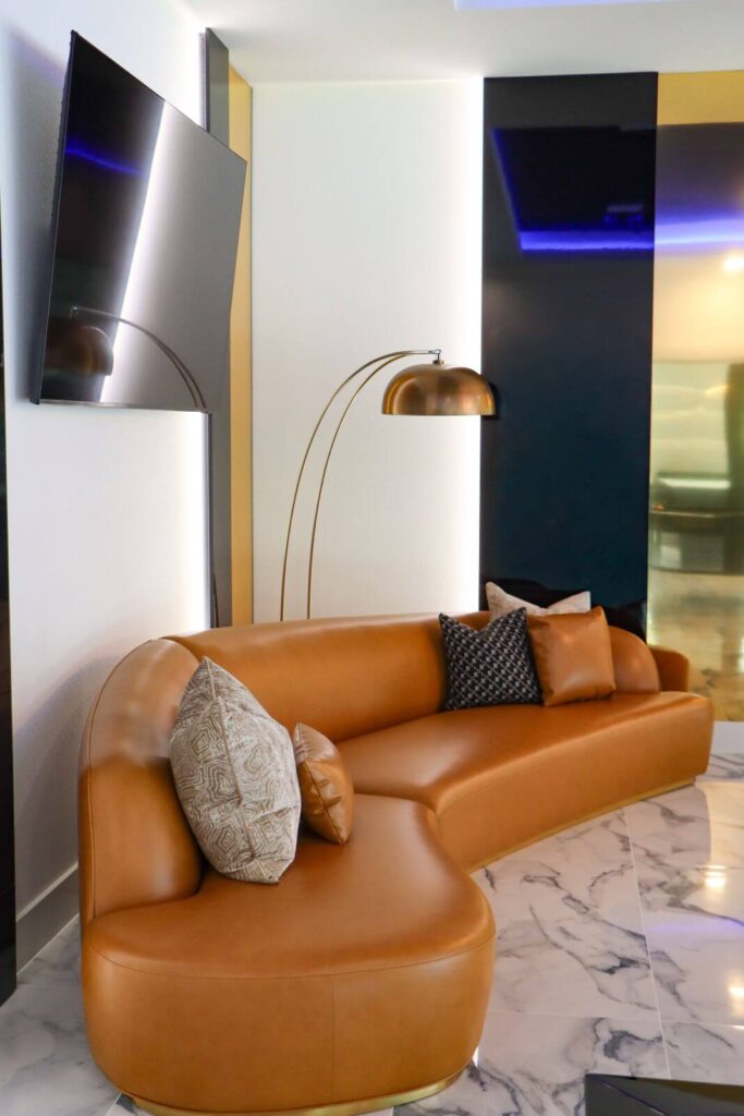 Curved designer leather sofa in the luxury entertainment room at Flaava House featuring custom lighting and contemporary furnishings.