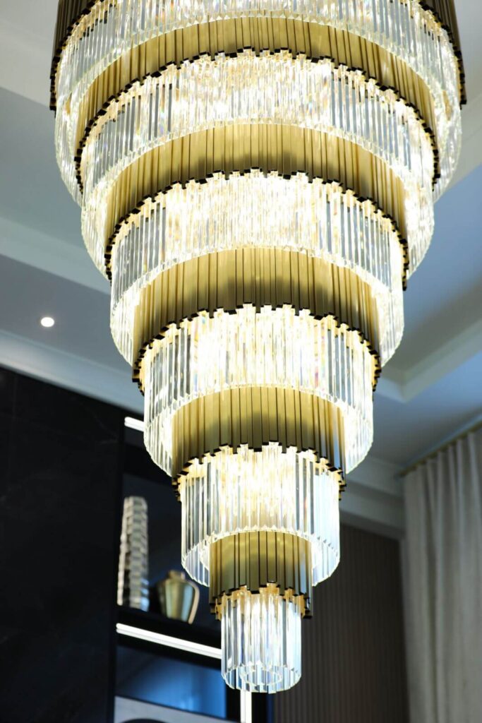 Custom multi-tier crystal chandelier suspended in the double-height great room of Flaava House, a luxury residence designed by Zamira Ariza in Lady Lake, Florida.