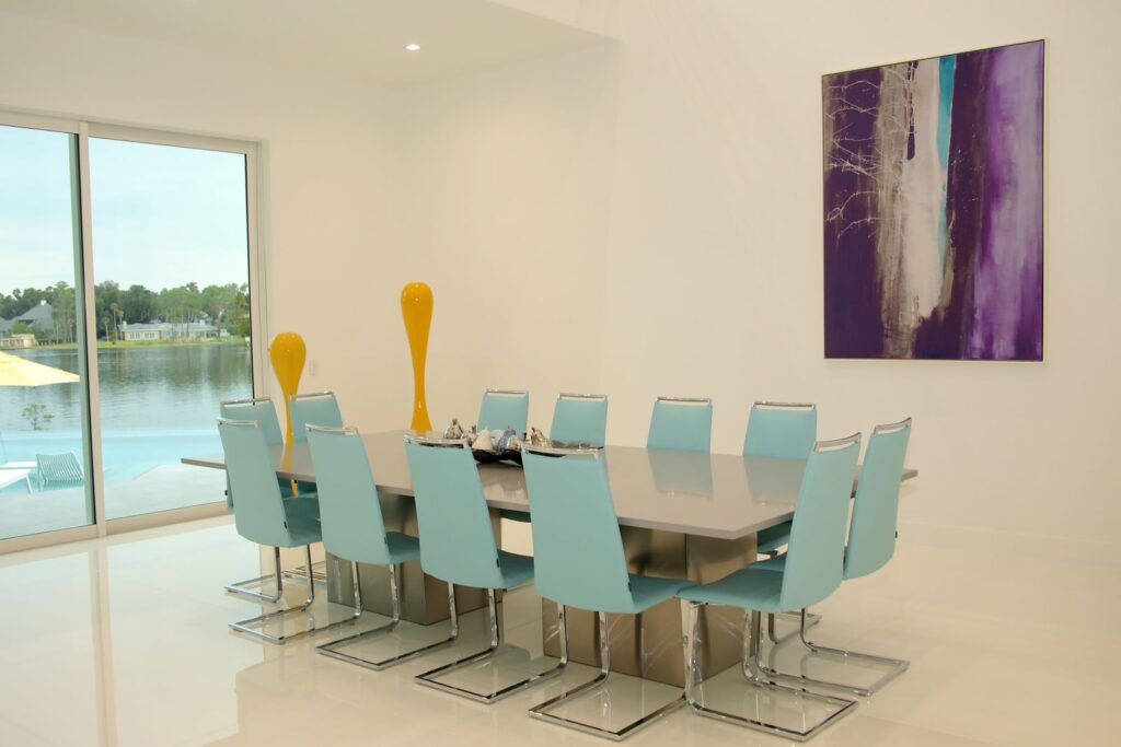 Contemporary dining room with custom table, statement artwork, and lake views inside Canvas Sur in Windermere, Florida.