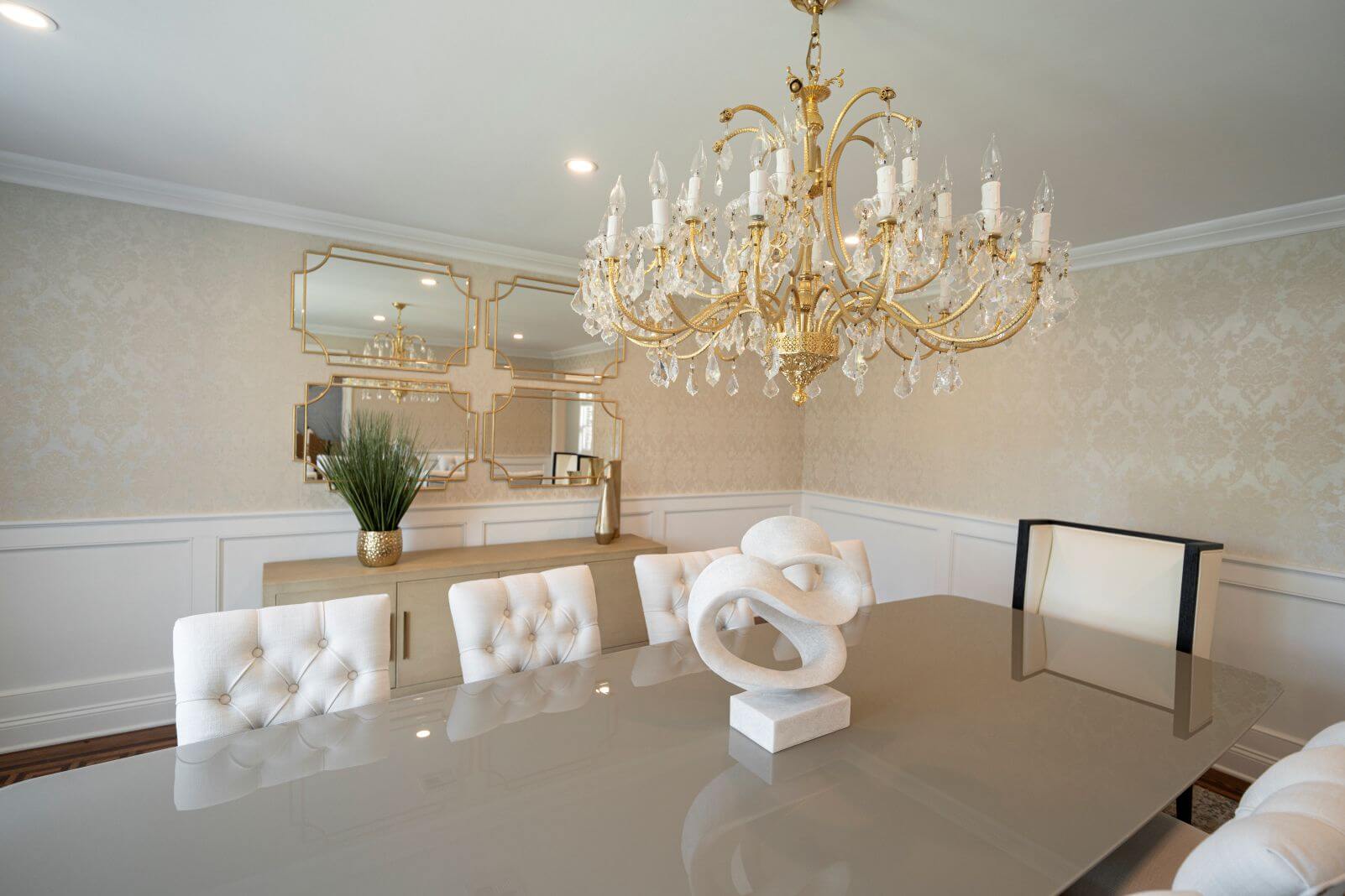 Luxury dining room featuring custom furnishings, mirrored wall décor, designer chandelier, and contemporary accessories.