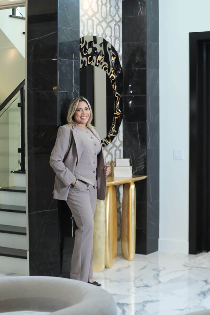 Luxury residential entryway featuring a custom Portuguese console table, designer mirror, black marble architectural columns, and contemporary finishes by Zamira Ariza.